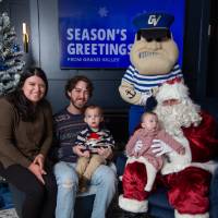 Parents with two young children smile with Santa and Louie